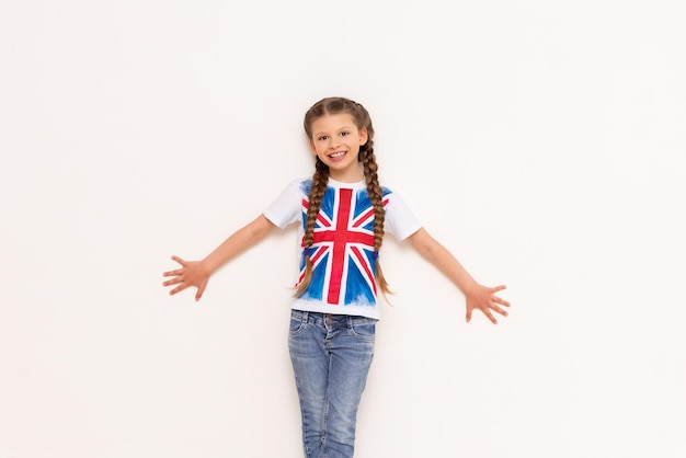 English for school children A little girl with the flag of Great Britain leans on your advertisement on a white isolated background