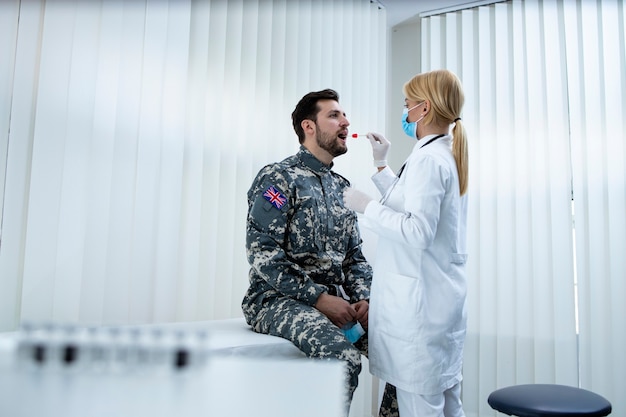 Soldato inglese in uniforme che fa il test pcr presso l'ufficio dei medici durante l'epidemia di virus covid19