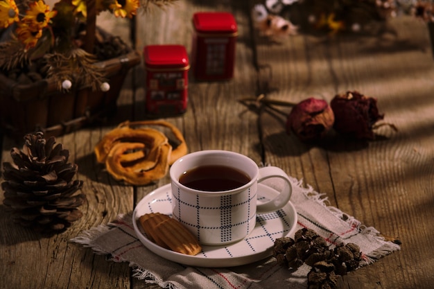 English Tea Time. Cup of tea with cookies on wooden table, rustic homemade interior.