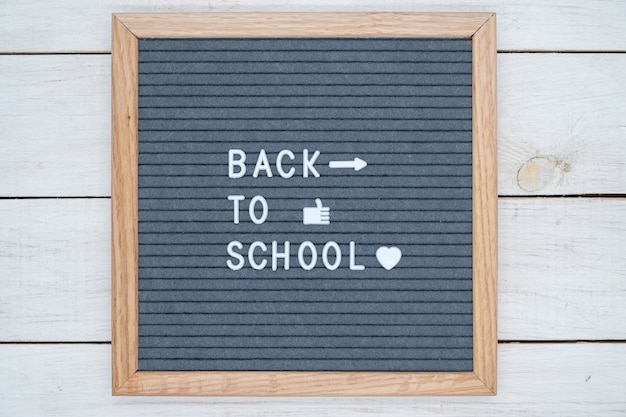 Photo english text back to school on a gray felt board in white letters and symbols like, heart and arrow