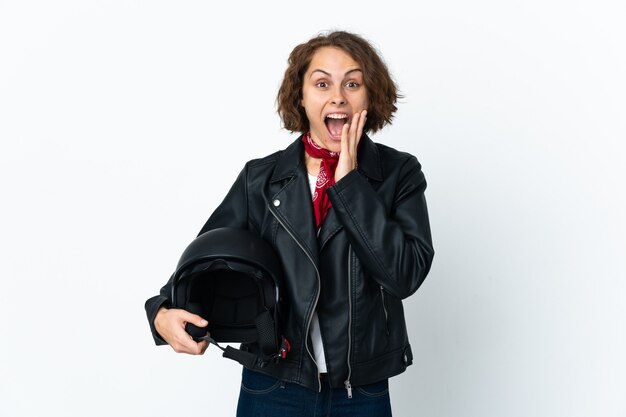 English woman holding a motorcycle helmet isolated on white background with surprise and shocked facial expression