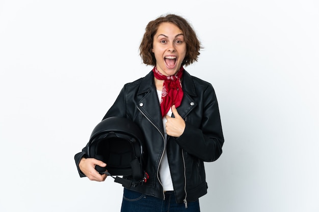 English woman holding a motorcycle helmet isolated on white wall with surprise facial expression