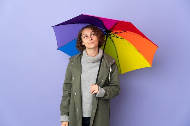 English woman holding an umbrella isolated and looking up