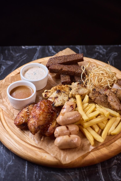 バーベキューの皿で,グリルチキン,ジューシーなソーセージ,脆いフライドポテトを楽しんでください