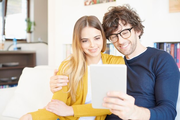 Photo enjoy browsing on the internet portrait of a lovely young couple sitting on the couch with their digital tablet at home and browsing on the internet