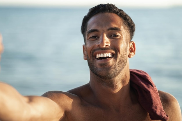 Enjoy summer vacation outdoor smiling portrait of relaxing young african man traveler on the beach making selfie portrait Love summer