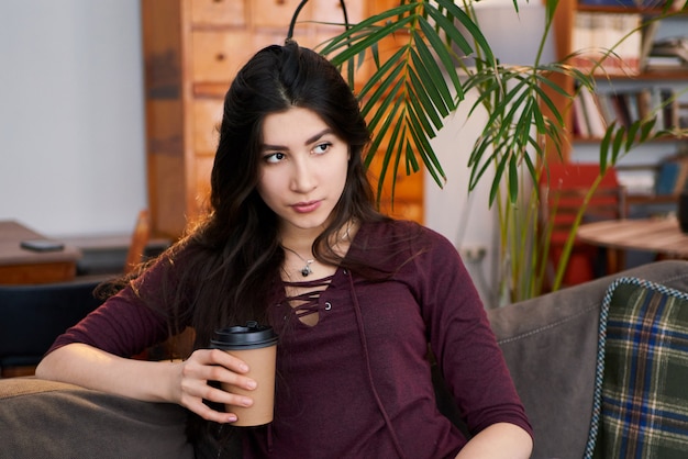 Enjoy weekend. Asian woman relaxing, drinking coffee and sitting on a couch