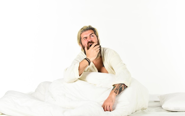 Enjoying beautiful morning guy in bathrobe at the bathroom handsome man in the morning bearded man wear white terry bathrobe sleeping on bed in hotel bedroom bed rest while sick man in underwear