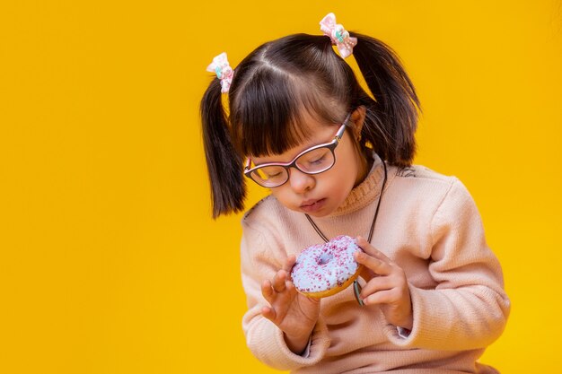 컬러 도넛을 즐기고 있습니다. 분홍색 뿌리로 파란색 도넛을 물고 정신 장애가있는 집중된 아가씨