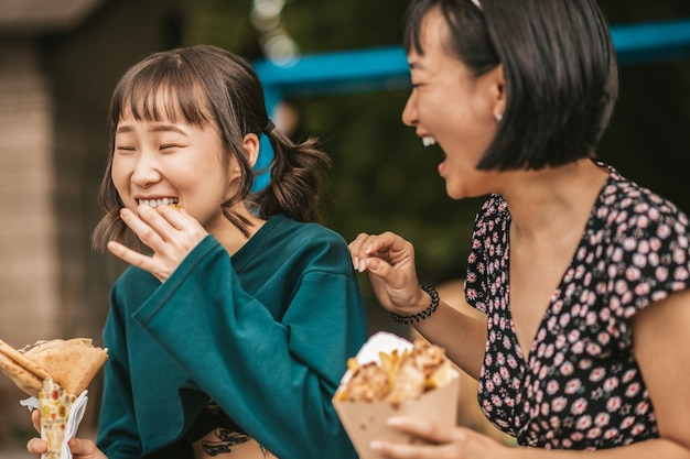 Enjoying the day. Cute young girls enjoying street food and looking entertained