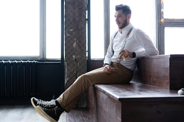 Enjoying free time. thoughtful young man in full suit looking\
away while sitting on the sofa at home.