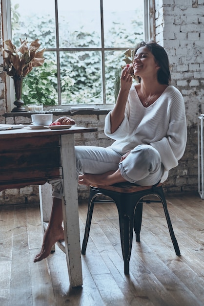 家で朝食を楽しんでいます。目を閉じて魅力的な若い笑顔の女性