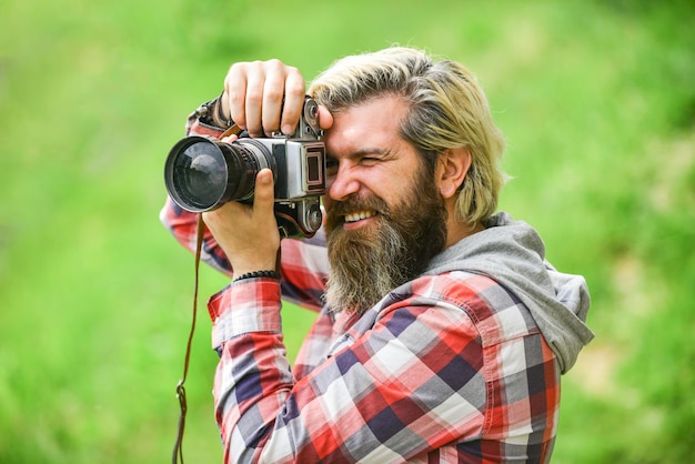 Enjoying hot day bearded man hipster take photo photo shooting outdoor brutal man traveler with retro camera photography in modern life travel tips professional photographer use vintage camera