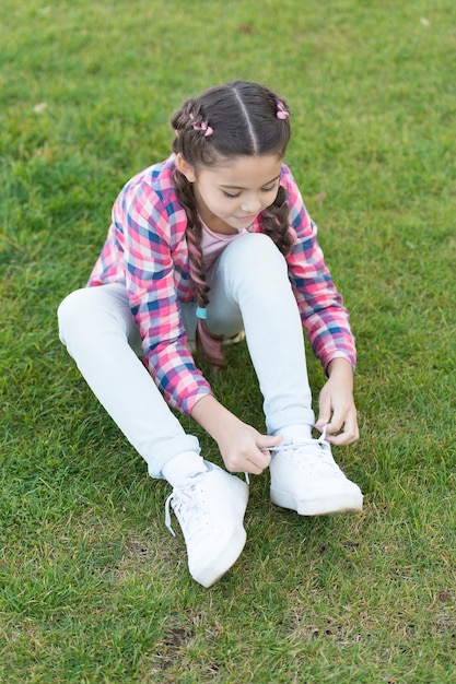 Enjoying leisure time small girl relax on green grass Parks and outdoor Spring nature Summer picnic Small school girl with trendy hair happy childhood total relaxation leisure activities