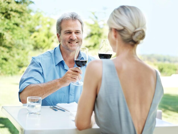 Photo enjoying a lunch date happy mature couple toasting their love with two glasses of wine while outdoors