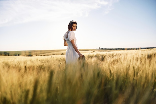 Enjoying the nature Beautiful young bride in white dress is on the agricultural field at sunny day