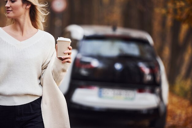 自然を楽しむ。女の子は車で秋の旅行をしています。森の中の現代の真新しい自動車。