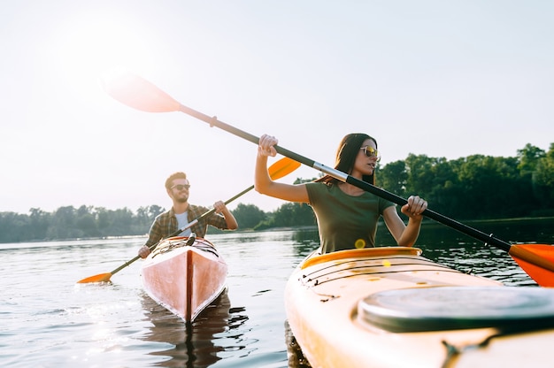 Enjoying nice day on the lake. Beautiful young couple kayaking on lake together and smiling