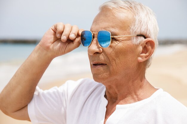 Enjoying the retirement. Happy senior man walking on the beach.