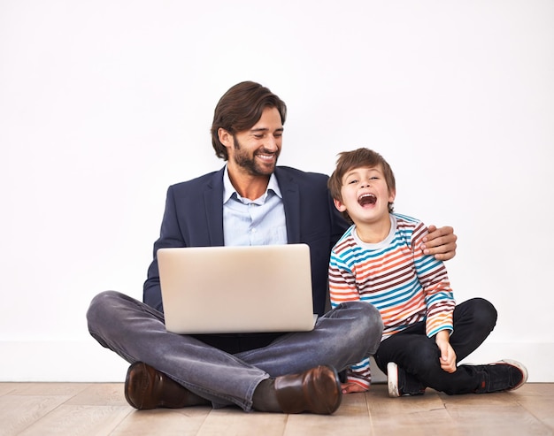 재미있는 온라인 비디오 즐기기 노트북을 들고 바닥에 앉아 있는 아버지와 아들