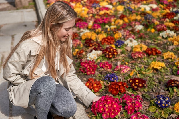 Enjoying spring's first blooms a young Caucasian woman gently touches a flower