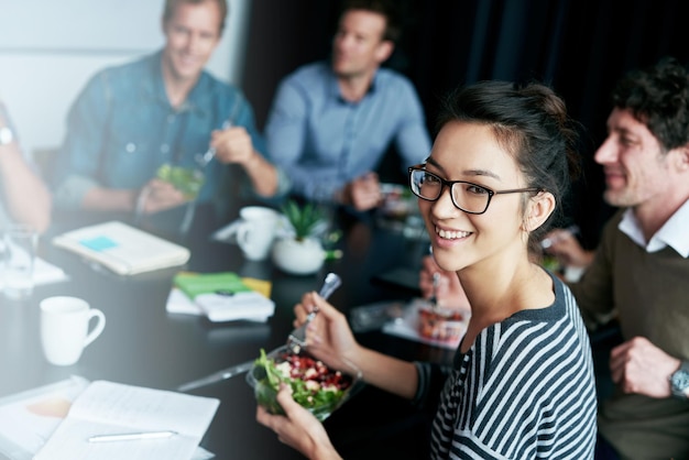 チームランチを楽しむ会議室のテーブルで同僚とランチを食べる若いサラリーマンの肖像画