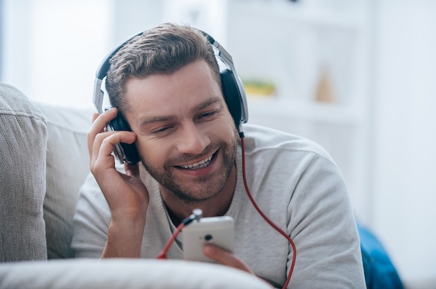 Godendo quella canzone. bel giovane uomo sorridente in cuffia che ascolta la musica