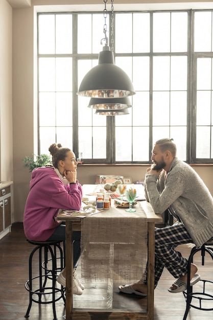 Enjoying time. good-looking happy father and daughter enjoying\
their time together sitting in kitchen