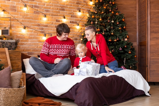 Enjoying time together on holidays. Happy mother, father and little child near Christmas tree.