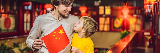 Enjoying vacation in china happy tourists dad and son with a chinese flag on a chinese background