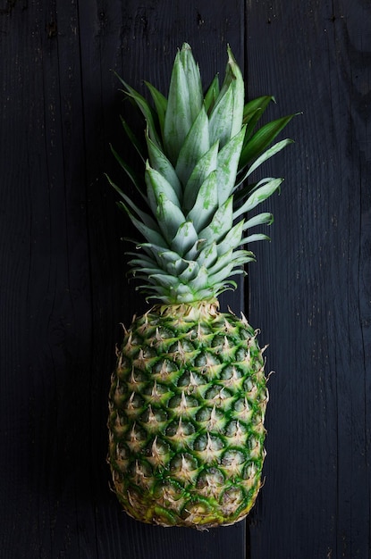 Enkele ananas over zwarte houten tafel