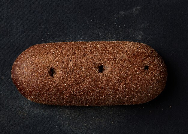 Foto enkele hele volledige rogge donker brood geïsoleerd op zwarte achtergrond