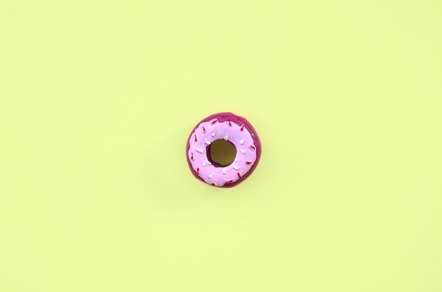 Enkele kleine plastic donut ligt op een kleurrijke pastelkleur. Plat leggen minimale samenstelling. Bovenaanzicht.