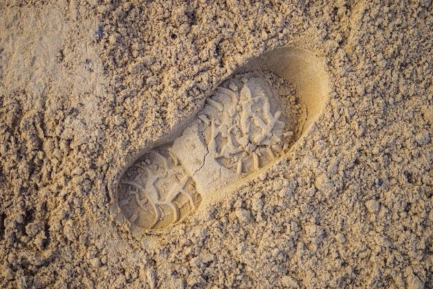 Enkele mannelijke voetafdruk Voetafdruk van schoen of spade in zand Achtergrond