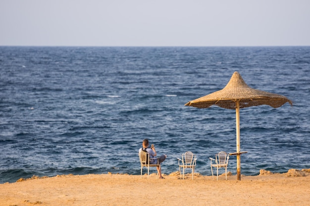 Enkele parasol en een man die aan zee zit