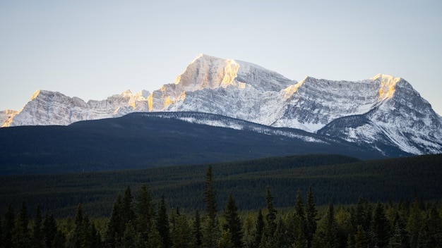 Enorme rotsachtige berg die de eerste zonnestralen opvangt op een koude winterochtend breed Banff NP Canada