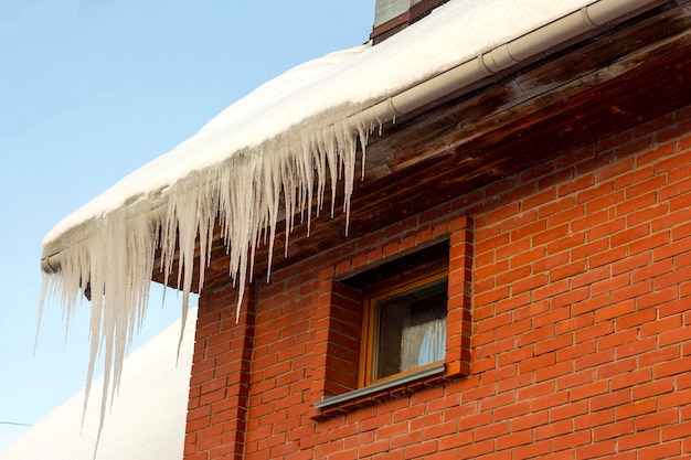 Enorme scherpe ijspegels hangen aan het dak van een woongebouw