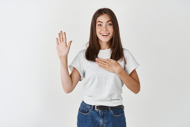 Enthousiast schattig meisje beloof dat ze de waarheid vertelt, druk een hand op het hart, handpalm optillen en vloeken