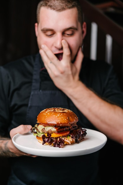 Enthousiaste chef-kok met een bord met heerlijke hamburger