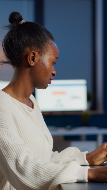 Enthusiastic african engineer analysing cad software to design a 3D concept of container working overtime in start-up company for prototype. Overworked woman studying in office using technology