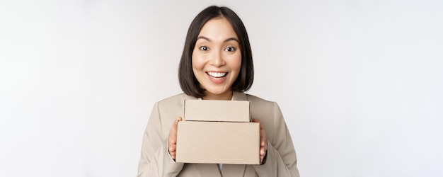 Enthusiastic asian businesswoman giving customer order boxes standing against white background Copy space