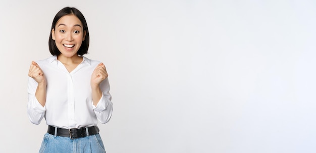 Enthusiastic asian woman rejoicing say yes looking happy and celebrating victory champion dance fist