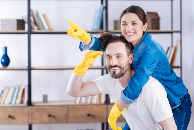 Enthusiastic cheerful glad couple playing while putting on gloves and laughing