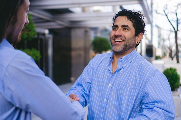 Foto entusiasta uomo latino di mezza età che stringe la mano a un potenziale cliente