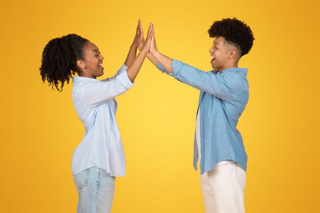 Enthusiastic young african american woman and man highfiving each other