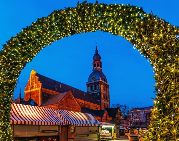 ラトビアの冬のリガの夜のクリスマスマーケットとリガ大聖堂への入り口。