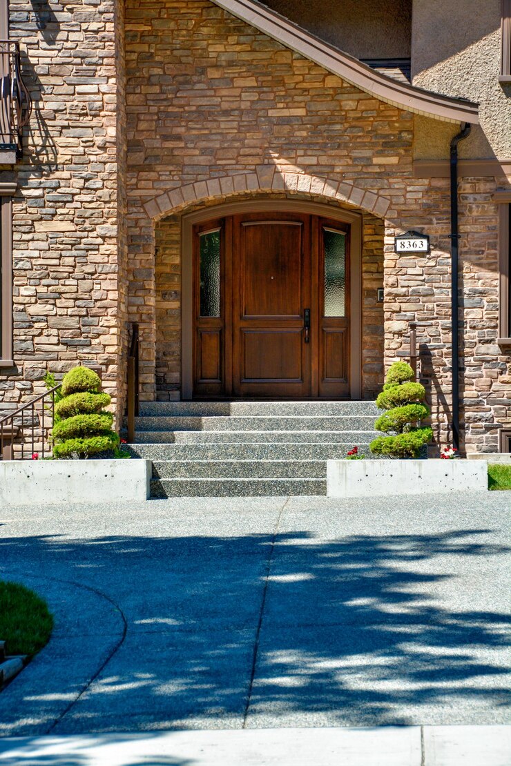 Entrance door of luxury house with concrete door steps and decor trees by sides