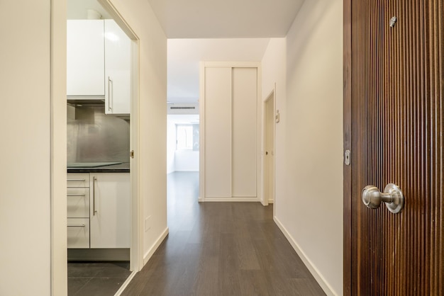 Entrance hall of a house with a solid wood door access in the first instance to a kitchen and then to a corridor with builtin wardrobes and windows through which light enters in abundance