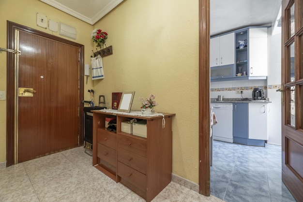 Entrance hall of a residential house with walls painted yellow with gotelet and a sideboard with mirrors in the background