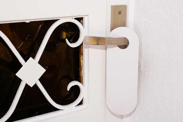 Photo entrance home with white door hanger of hotel room with empty sign please do not disturb